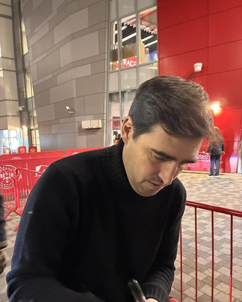 Andoni Iraola signing autographs outside a stadium in December 2025