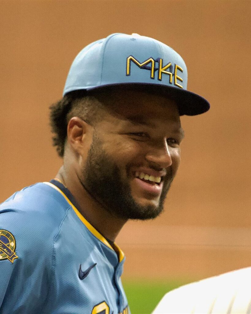 Jackson Chourio smiling in a light blue Milwaukee Brewers City Connect cap and jersey