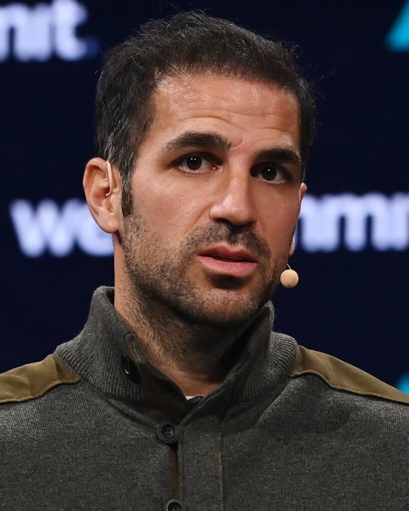 Cesc Fabregas speaking on stage at Web Summit 2023, in a dark green jacket
