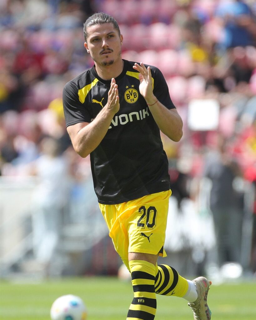 Marcel Sabitzer in a black Borussia Dortmund warm-up shirt, clapping on the pitch