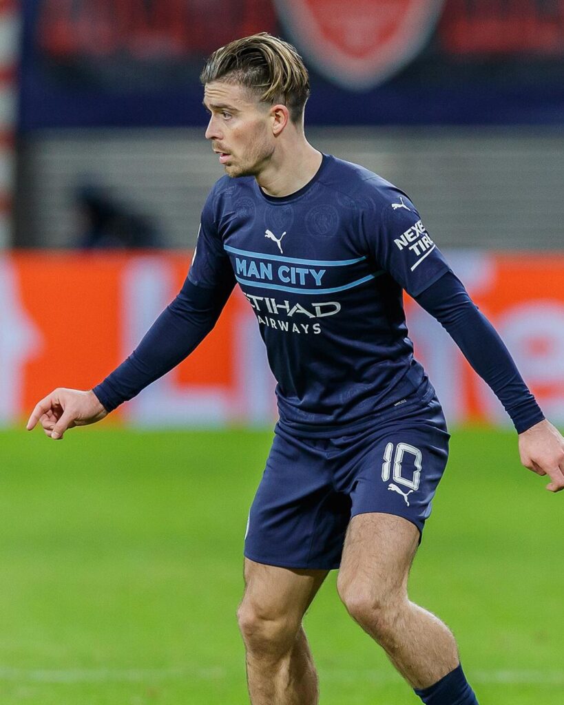 Jack Grealish in a dark blue Manchester City kit, with the ball at his feet during a Champions League game