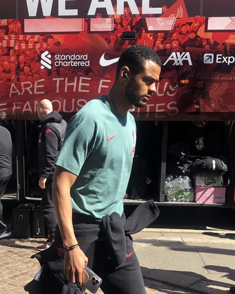Cody Gakpo in a green Liverpool T-shirt, walking past the team bus