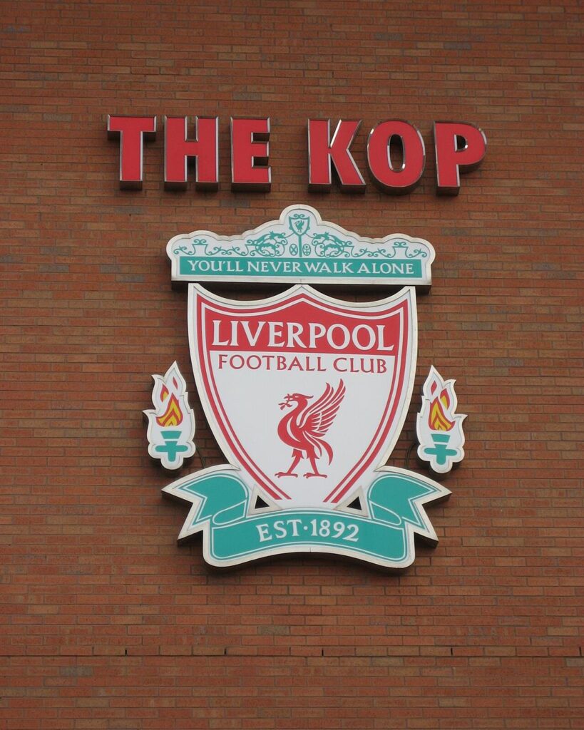 The Kop sign and the Liverpool crest on the brick wall at Anfield