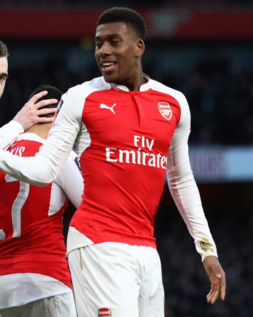 A young Alex Iwobi smiling in a red and white Arsenal kit during a match