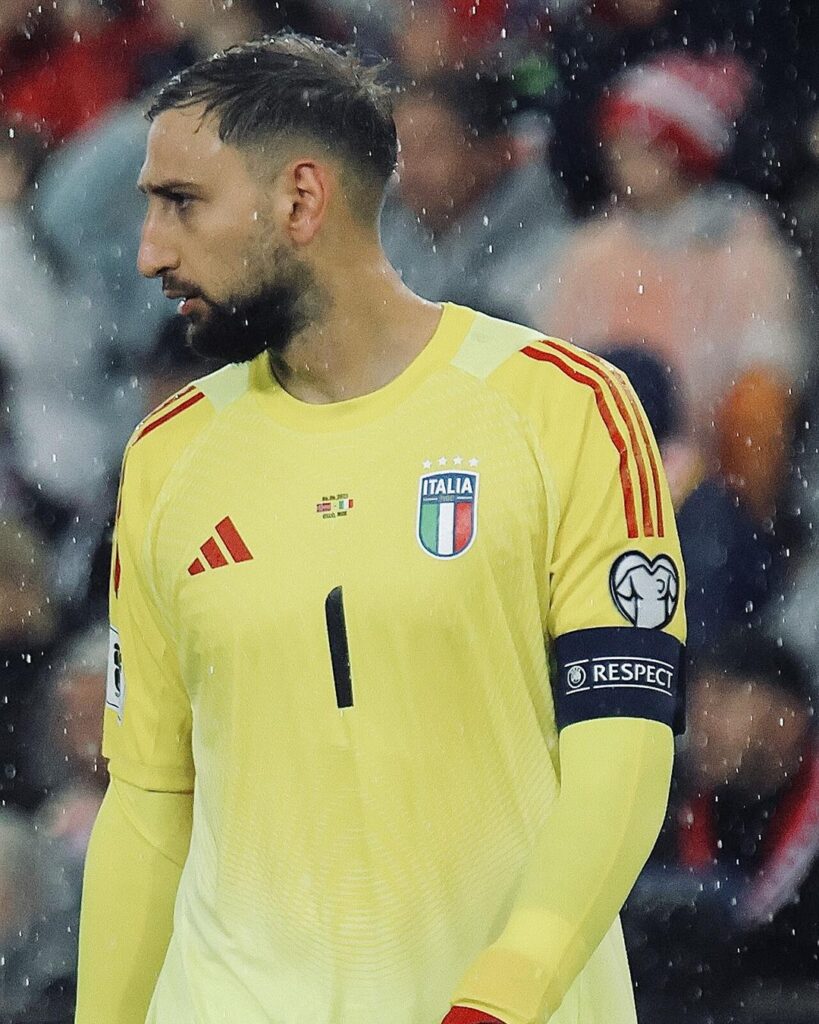 Gianluigi Donnarumma in a yellow Italy goalkeeper shirt with the captain's armband, in the rain