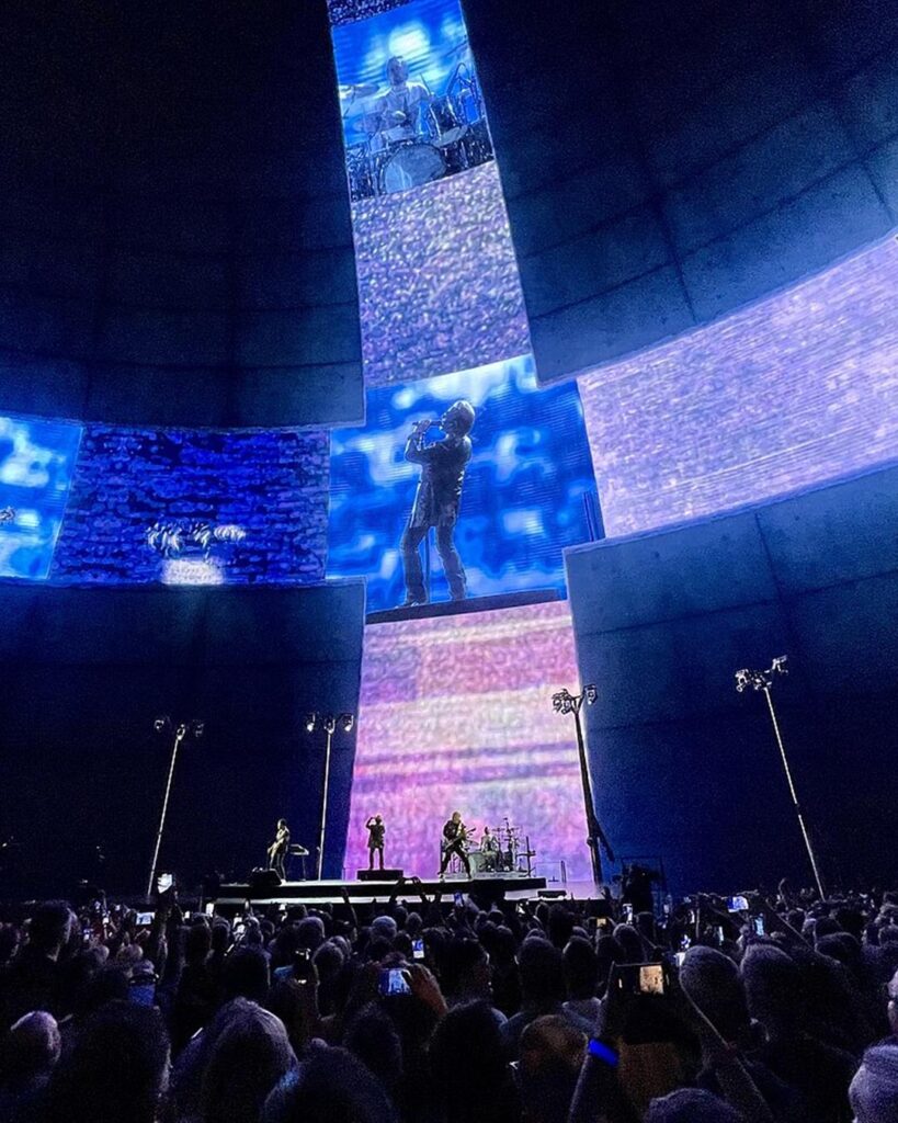 U2 on stage at Sphere in Las Vegas under huge video screens, with the crowd in front, 2023